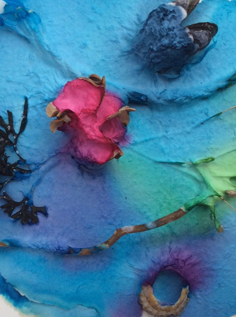 Photograph of turquoise, pink, purple and green detail of handmade paper with embedded pieces of mussel shell, jetsom and flotsam and seaweed.